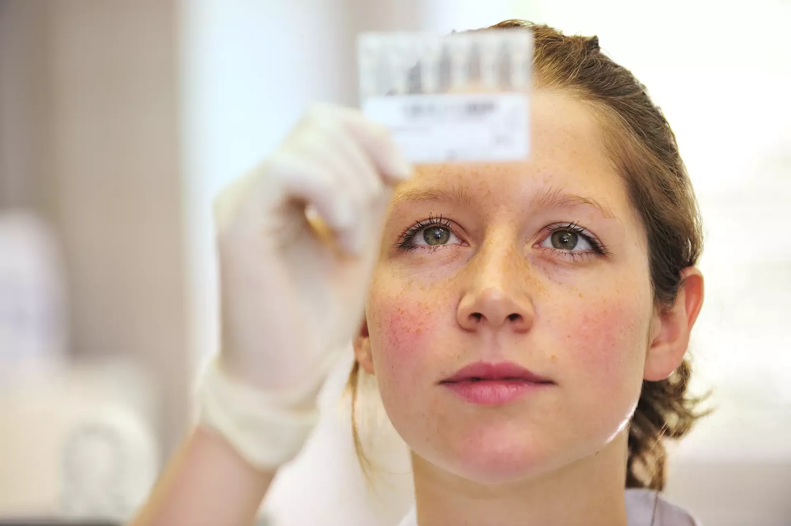 Eine Wissenschaftlerin und ein Wissenschaftler arbeiten hinter einer Glasfassade und mischen Chemikalien mit Großgeräten.